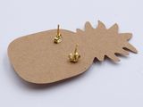 a close up of a pair of gold pineapple earrings on a white surface