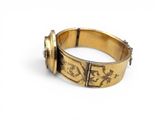 a close up of a gold bracelet on a white surface