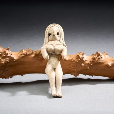 une figurine représentant une femme tenant un morceau de bois