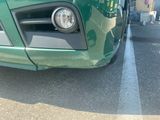 a close up of a green car parked in a parking lot