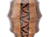 un vase marron orné de feuilles noires sur fond blanc