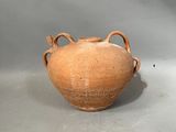 un vase brun posé sur une table à fond gris