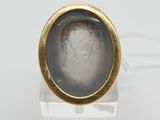 une image représentant une bague en or sur laquelle figure le portrait d'un homme dans un verre