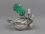 gros plan d'une bague avec une pierre verte et des diamants