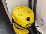 un aspirateur jaune posé par terre près d'un mur blanc