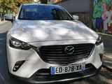 the front of a white mazda vehicle parked on the side of a road
