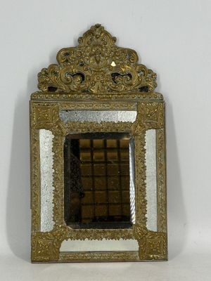 un petit miroir au cadre doré accroché à un mur blanc