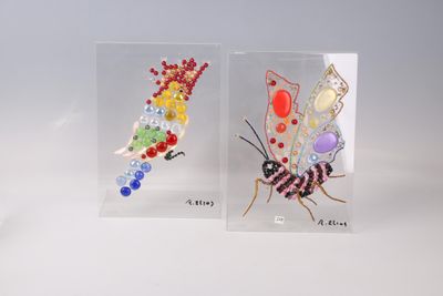 deux petits insectes en verre, de couleurs et de tailles différentes, posés sur une surface blanche