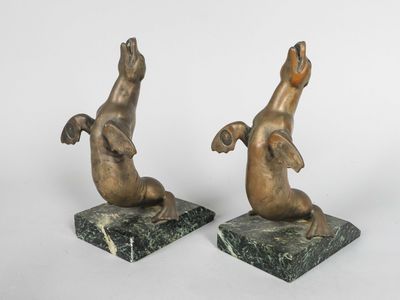 paire de sculptures en bronze représentant un chien et un chat, posées sur des socles en marbre