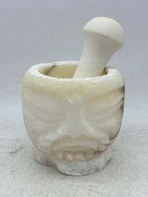 Mortier en albâtre à décor sculpté d'un visage et pilon