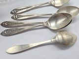 five silver spoons are lined up in a row on a table