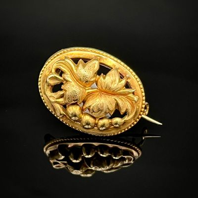 une image représentant une broche en or ornée de fleurs sur un fond noir