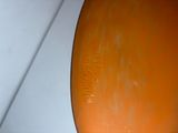 a close up of an orange vase on a white surface