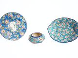 trois compositions florales bleues et roses sur une assiette et un bol