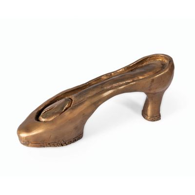 une image représentant un objet en bronze en forme de chaussure sur fond blanc