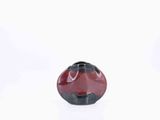 a red and black vase sitting on a white surface