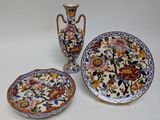 three plates and two vases sitting on a table