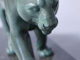 a green statue of a cat on a marble base