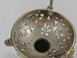 an antique brass incense burner on a stand on a white surface