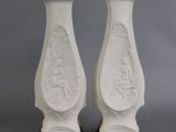 une paire de vases blancs ornés de motifs sur fond gris