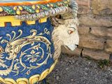 a blue and yellow vase with a ram head on it