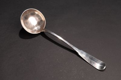une cuillère en argent dont le manche repose sur une surface noire