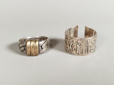 two silver rings with gold bands on a white surface
