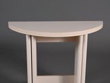 une table en bois blanche au plateau incurvé, sur fond gris