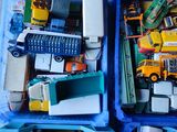 de nombreux camions miniatures dans un bac bleu posé par terre