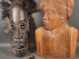 two wooden masks and a wooden head with feathers on a gray background
