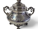 une théière en argent avec un couvercle, posée sur un socle