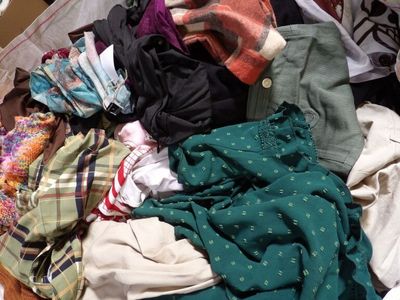 a pile of clothes sitting on the floor next to a bed