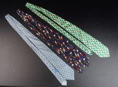 quatre cravates de couleurs différentes suspendues à un porte-cravates posé sur une surface noire