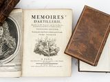 two old books and a leather case on a white surface