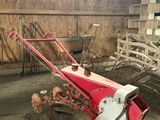 un tracteur rouge équipé d'une charrue, dans une grange