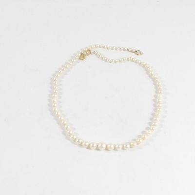 un collier de perles blanches avec un fermoir en or sur fond blanc