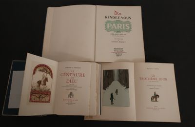 Trois livres sont ouverts sur une table noire, sur fond noir.