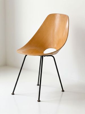 a wooden chair with black legs in a white room
