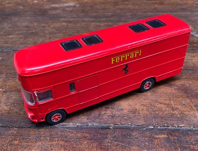 un petit bus rouge posé sur une table en bois