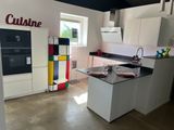 une cuisine blanche avec un plan de travail noir et un réfrigérateur coloré