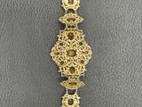 a close up of a gold bracelet on a gray surface