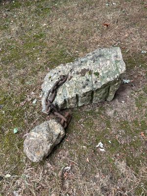 a large rock with a chain attached to it in the grass