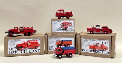 quatre petits camions rouges posés sur des cartons, sur une surface blanche