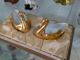 une vitrine en verre sur laquelle sont posées deux figurines de cygnes en or