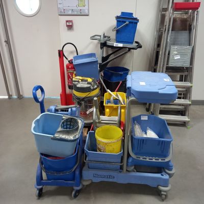 several buckets and mops are stacked on a cart in a room