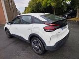 the rear end of a white car parked in a parking lot