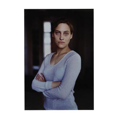 portrait d'une femme vêtue d'un pull bleu, les bras croisés