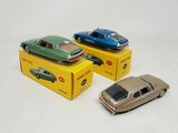 three toy cars sitting on top of boxes on a white surface