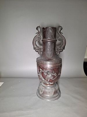 a silver vase with a face on it sitting on a table