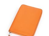 un carnet en cuir orange muni d'une fermeture à glissière, sur fond blanc